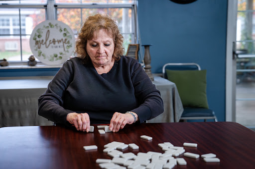 A woman carefully arranging dominoes on a table in a cozy indoor setting.