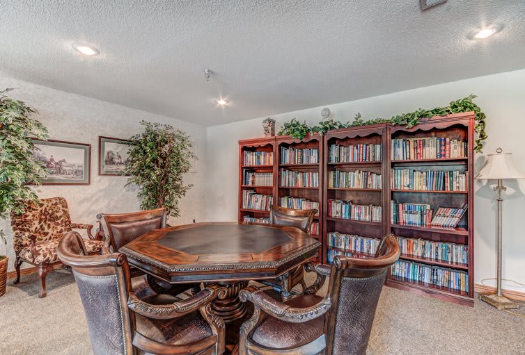 A cozy library room with bookshelves, a round table, and chairs.