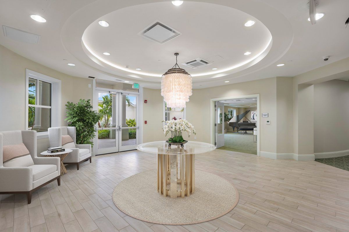 A modern, elegantly designed lobby with a central chandelier and decorative table.