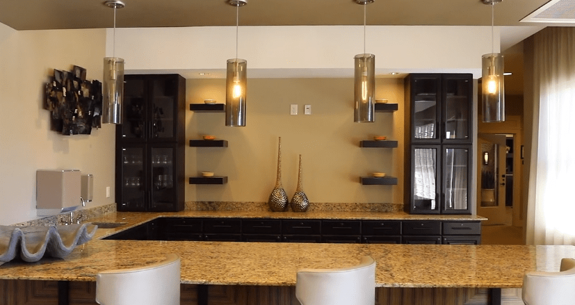 A modern kitchen interior with pendant lights, granite countertops, and decorative shelving.