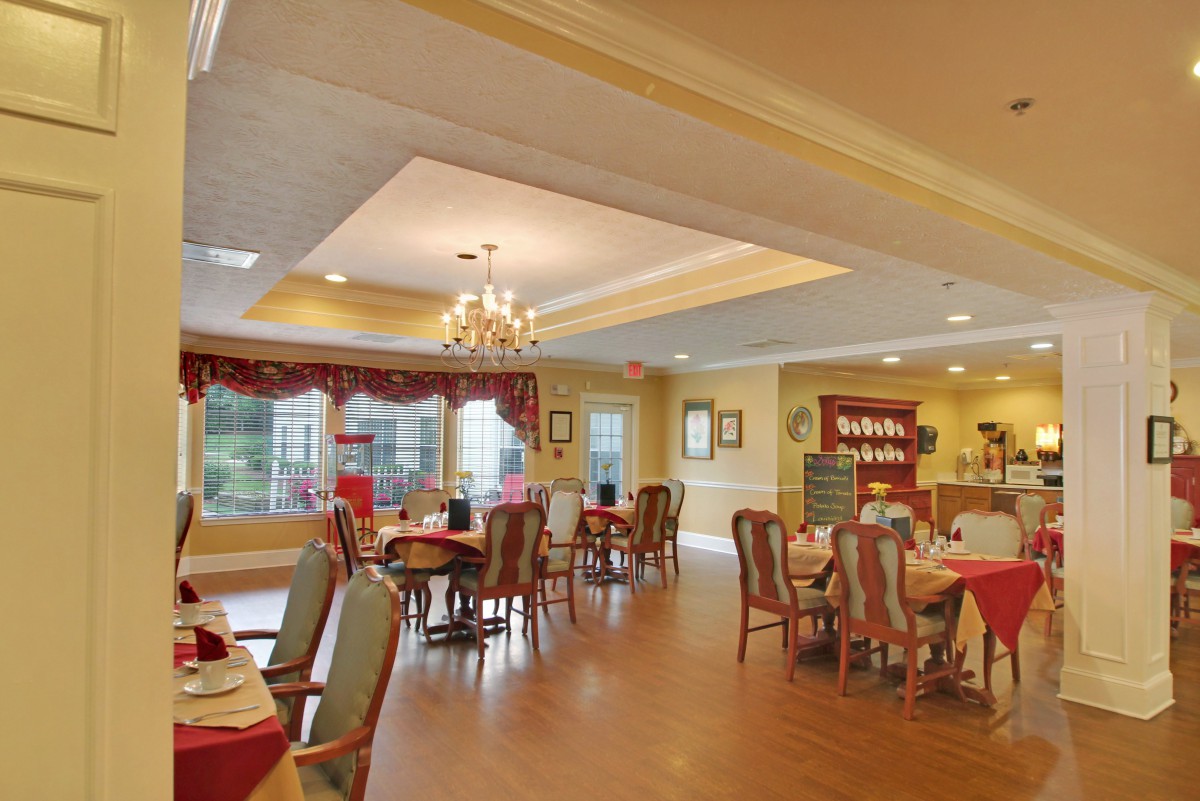 A cozy dining room with elegant chandeliers and well-arranged tables and chairs.