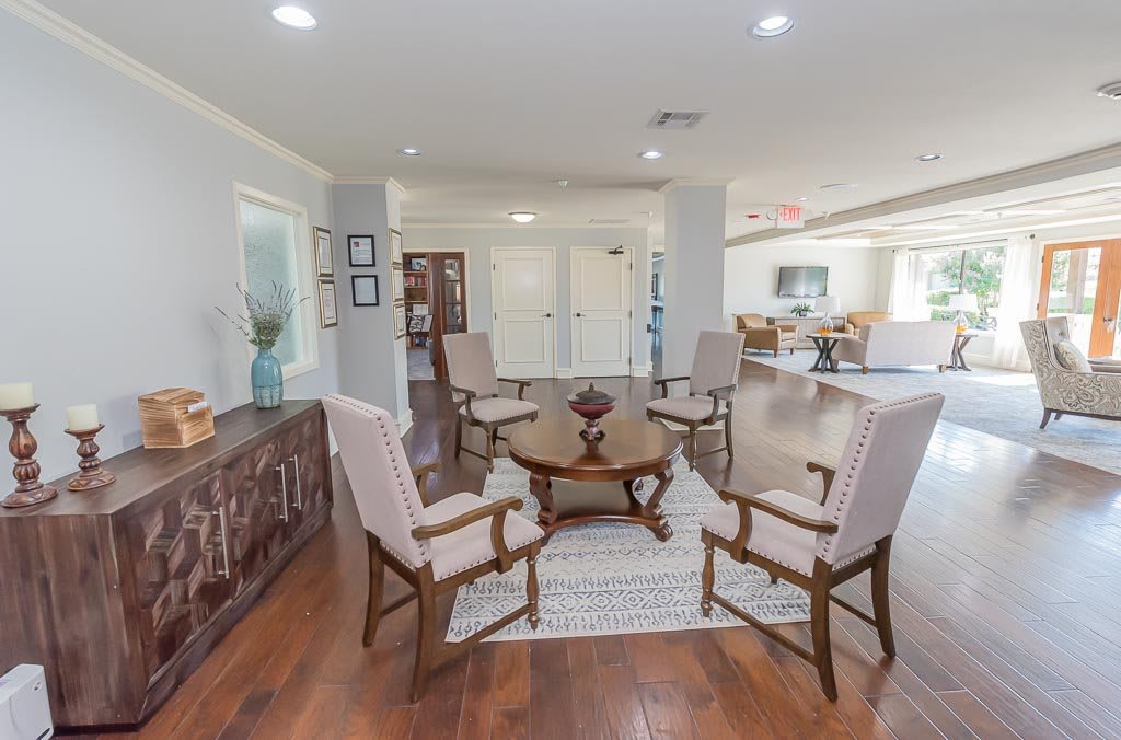 A cozy living room with a circular arrangement of chairs around a wooden table on a rug.