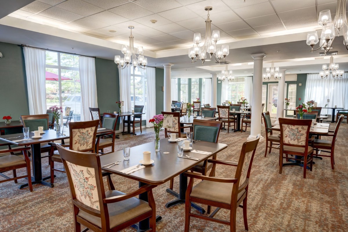 A well-decorated dining room with elegant chandeliers and neatly arranged tables and chairs.