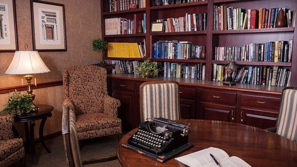 A cozy library office featuring a vintage typewriter on the desk amidst bookshelves.