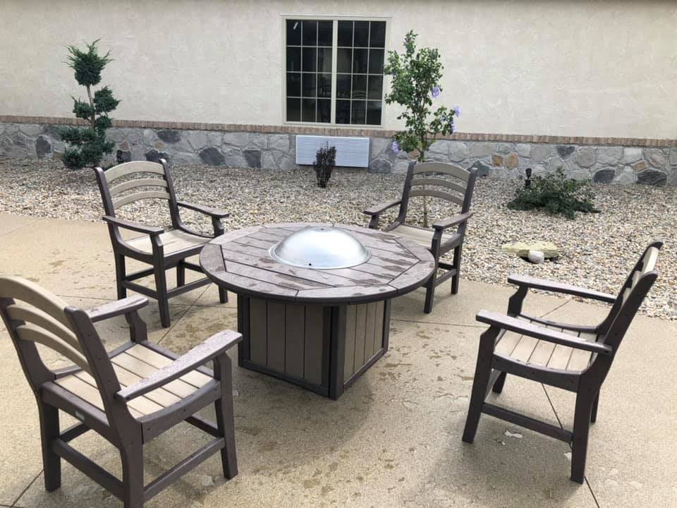 A cozy patio seating area with a circular table and four chairs, set in a backyard.