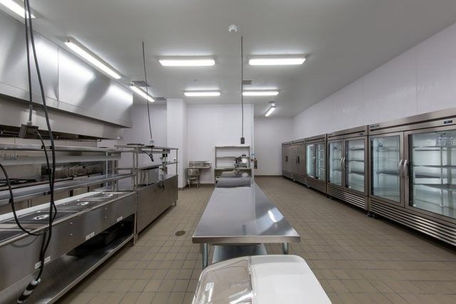A clean and empty commercial kitchen with stainless steel appliances and refrigeration units.