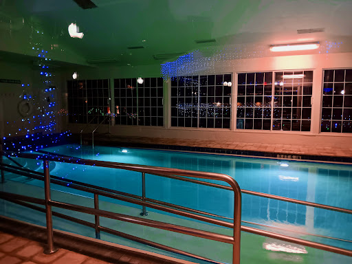 A serene indoor swimming pool illuminated with soft blue and orange lighting.