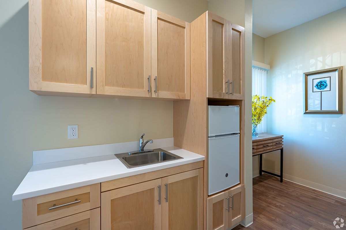 A modern kitchen with wooden cabinets, a sink, and a refrigerator.