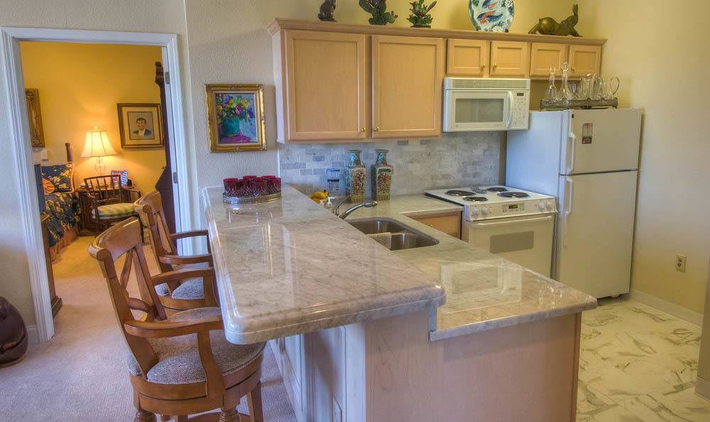 A cozy kitchen with wooden cabinets, a marble countertop, and bar stools.