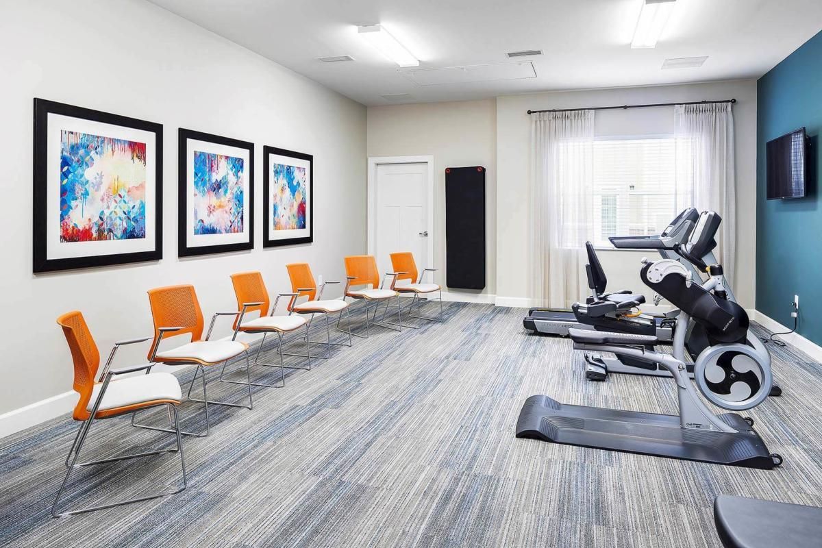 A modern gym interior with exercise equipment and seating area.