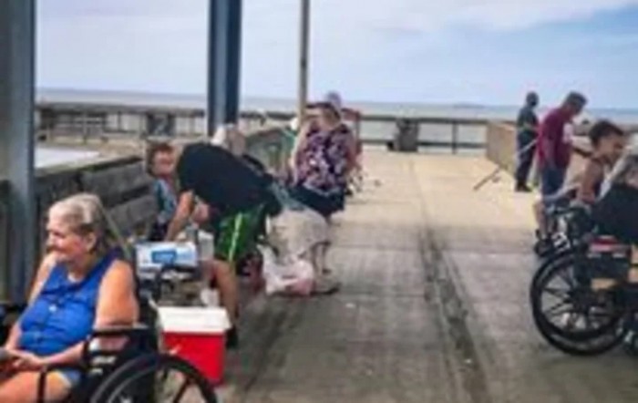People enjoying a day of fishing on a pier overlooking the ocean.