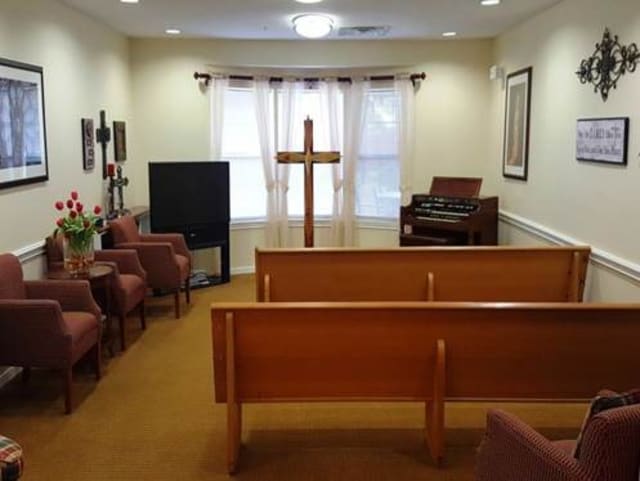A small chapel with pews, a cross at the front, and an organ in the corner.