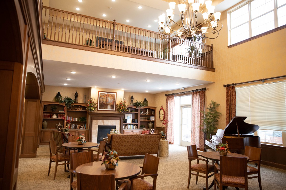 A spacious and elegantly decorated lounge area with a chandelier, fireplace, and comfortable seating.