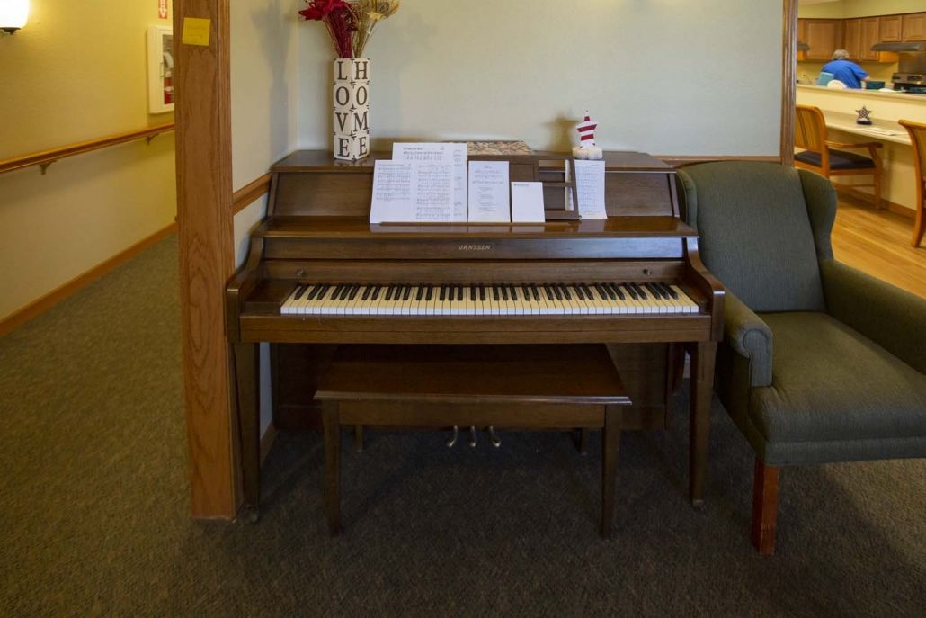 A piano with sheet music placed on the stand in a living room setting.