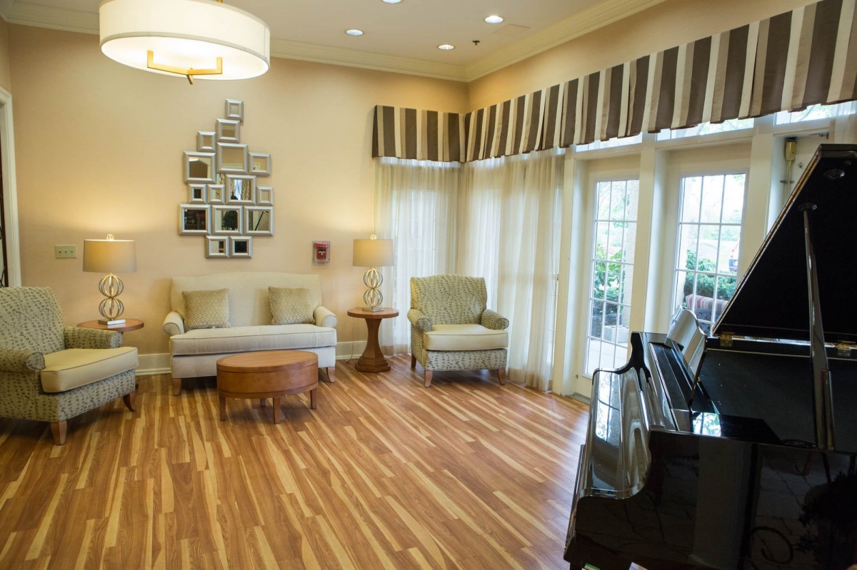 A cozy living room featuring a piano, elegant furniture, and a hardwood floor.