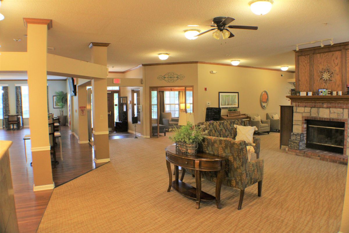 A spacious and well-lit living room with comfortable seating arrangements and a ceiling fan.