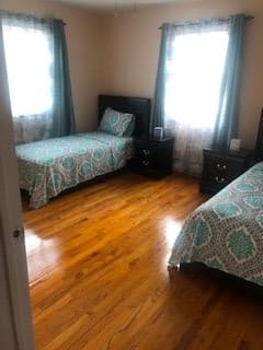 A cozy bedroom with twin beds and hardwood flooring.
