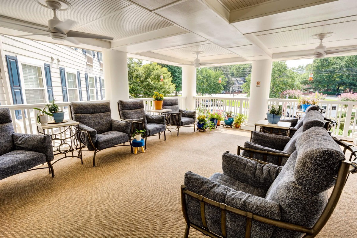 A spacious porch featuring comfortable seating and potted plants, providing a relaxing outdoor space.