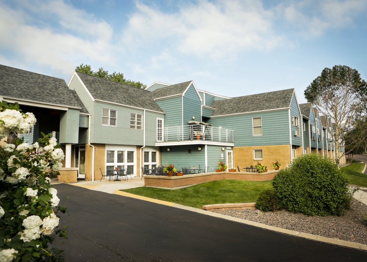 A modern apartment complex with well-maintained landscaping on a sunny day.
