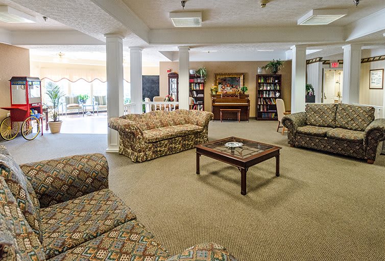 A spacious living room with patterned sofas, a wooden coffee table, and bookshelves by the fireplace.