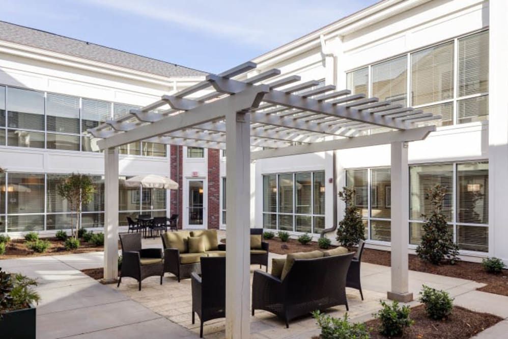 A modern outdoor patio with a pergola and comfortable seating area.