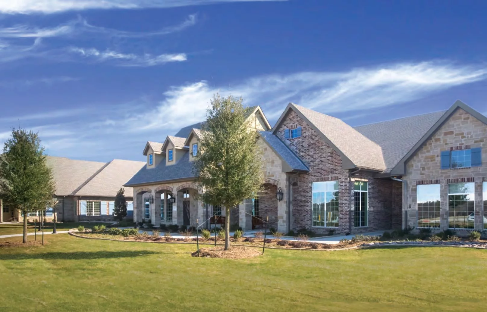 A beautiful, large brick house with a spacious yard under a clear blue sky.