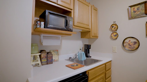 A compact kitchen featuring wooden cabinets, a microwave, and a coffee maker on the countertop.