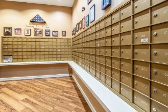 A room filled with rows of small mailboxes inside a post office, featuring a wooden floor and framed decorations on the walls.