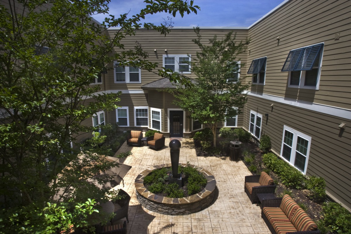 A cozy courtyard with a central fountain, surrounded by apartment buildings and outdoor seating.