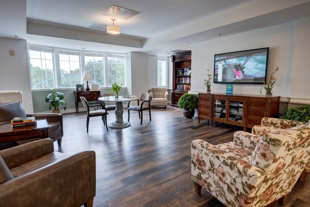 A cozy living room with a hardwood floor, featuring comfortable furniture and ample natural light.