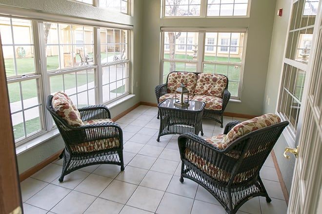 A cozy sunroom featuring wicker furniture and ample natural light streaming through large windows.