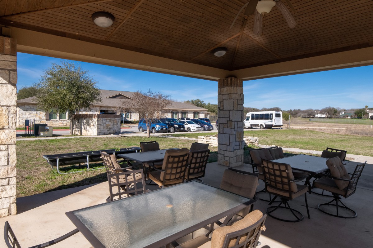 Outdoor patio area with tables and chairs under a covered pavilion.