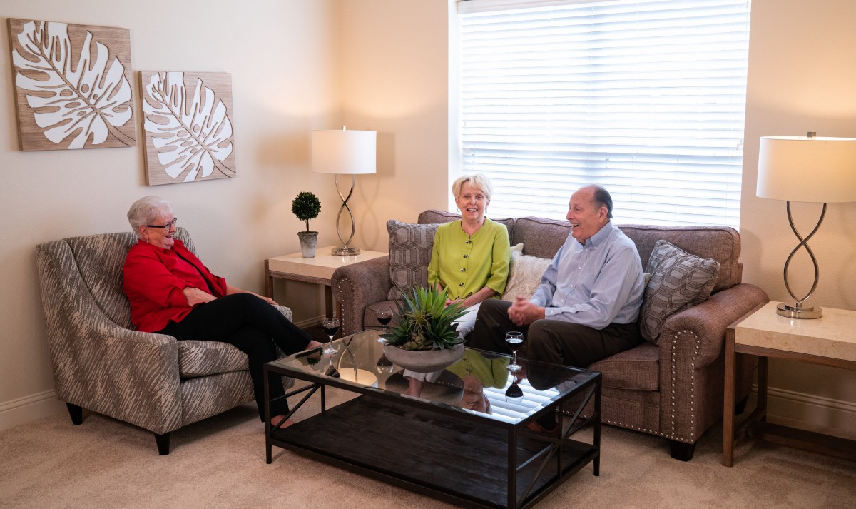 Three people sitting in a living room having a conversation.