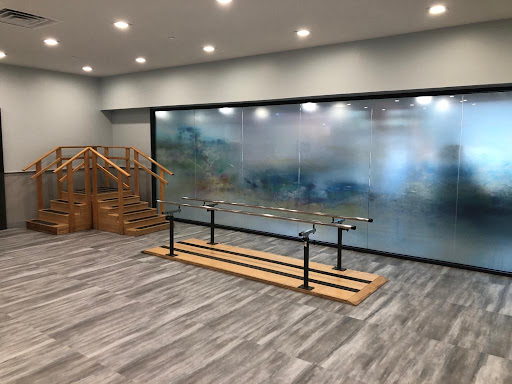 A contemporary interior featuring a wooden structure and a glass wall, illuminated by modern lighting.