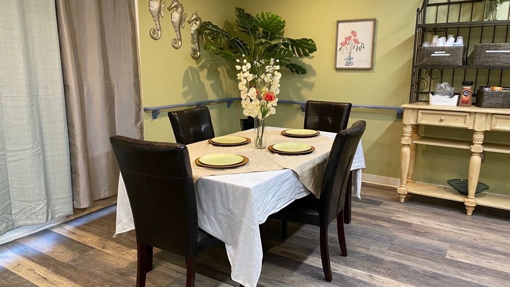 A neatly set dining table with four chairs, adorned with a floral centerpiece.