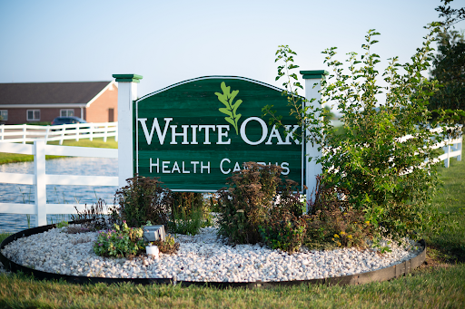 Entrance sign for White Oaks Health Care, surrounded by landscaped gardens.