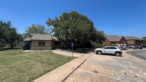 A peaceful residential scene showcasing a house with a large tree and parking space under a clear blue sky.
