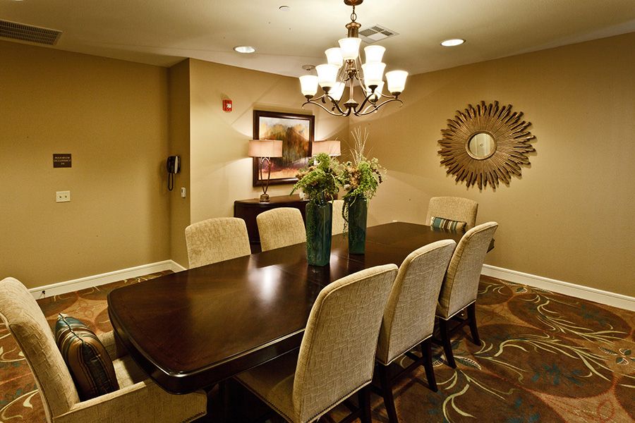 A stylish dining room featuring a dark wooden table, surrounded by upholstered chairs and illuminated by an elegant chandelier.