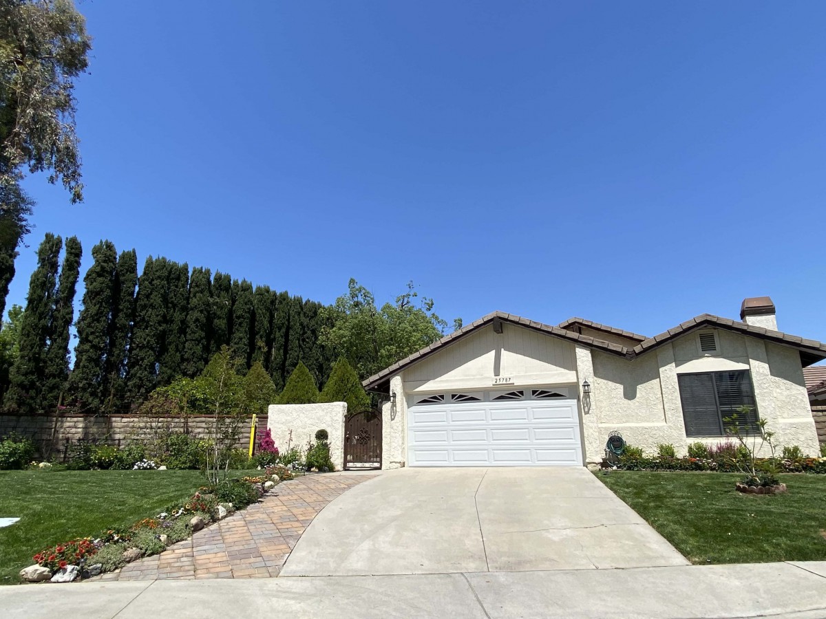 A suburban house with a garage and driveway on a clear, sunny day.