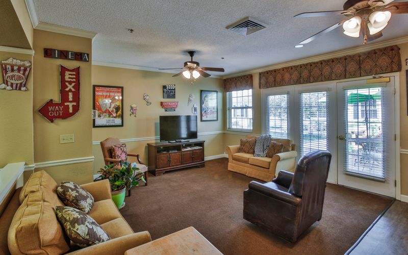 A cozy living room with comfortable seating, a TV, and a ceiling fan.