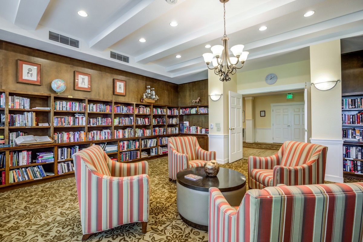 A cozy library reading area with striped armchairs and bookshelves.