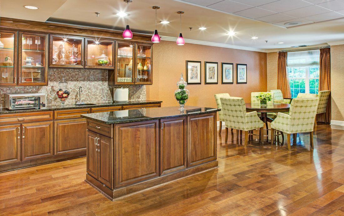 A stylish kitchen and bar area featuring wooden cabinetry, pendant lighting, and an adjacent dining space with hardwood floors.