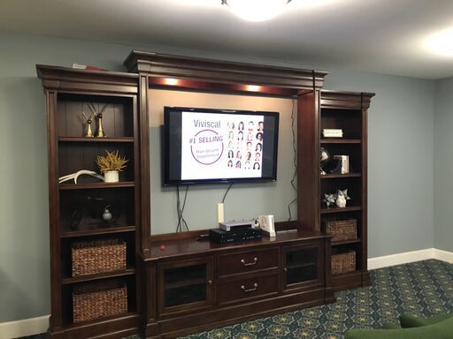 A well-organized entertainment center featuring a mounted TV and wooden shelves filled with decorative items.