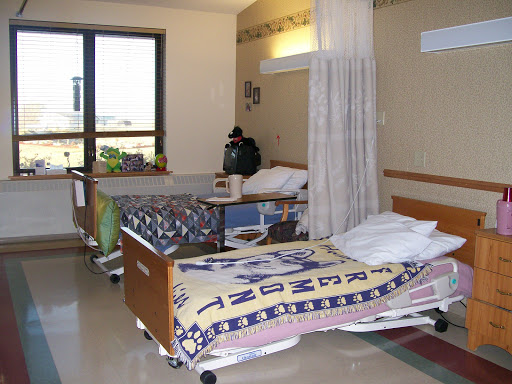 A view of a patient room in a hospital, featuring two beds and a window.
