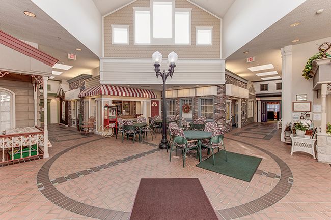 An indoor shopping area with tables, chairs, and decorative lighting.