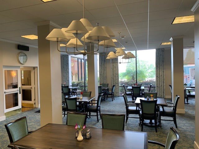 An empty dining area with tables, chairs, and large windows.