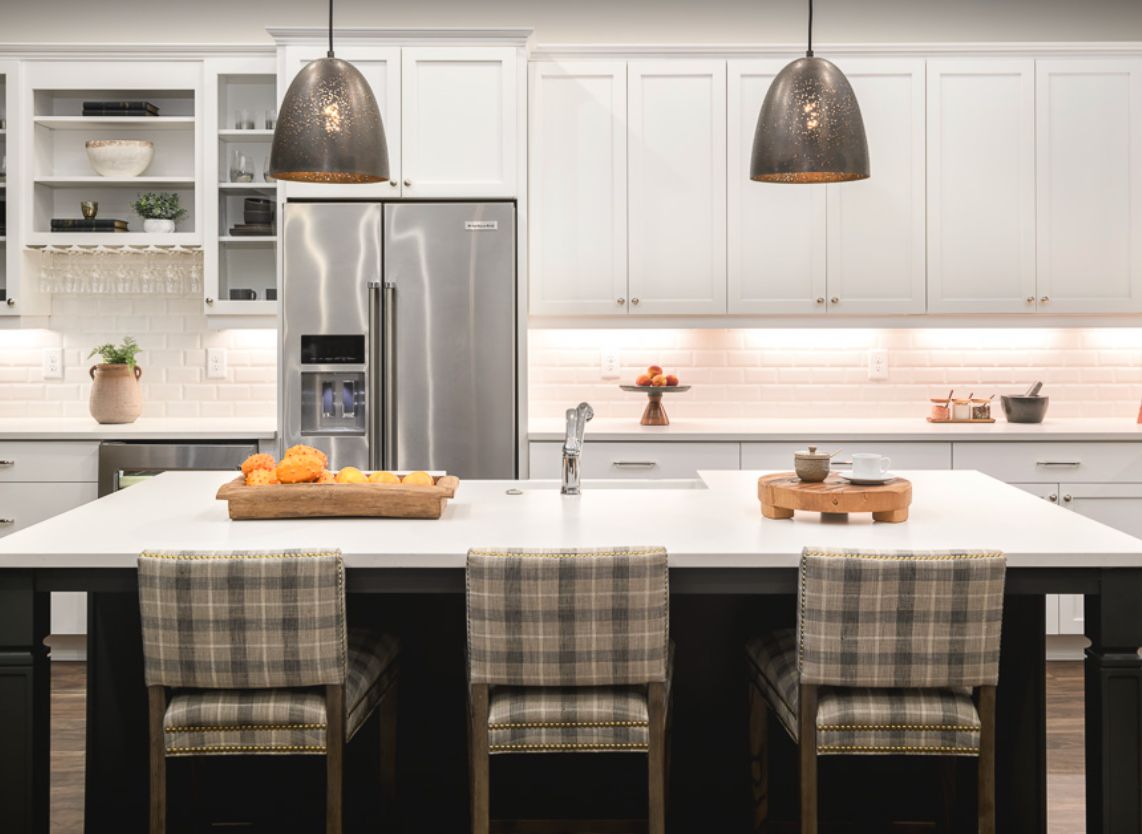 A modern kitchen with white cabinets, stainless steel appliances, and a central island with bar stools.