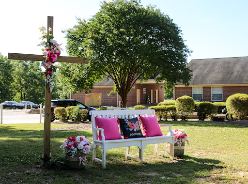 A serene outdoor space featuring a beautifully decorated bench and cross, perfect for reflection.