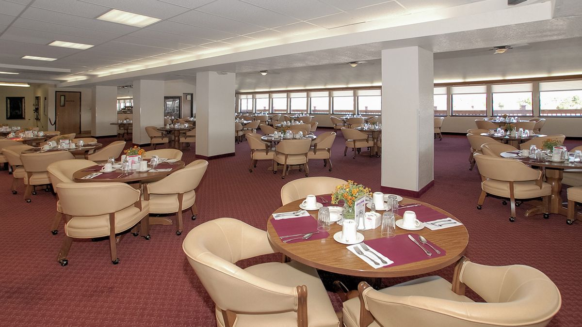 An empty dining area with round tables neatly set for guests.