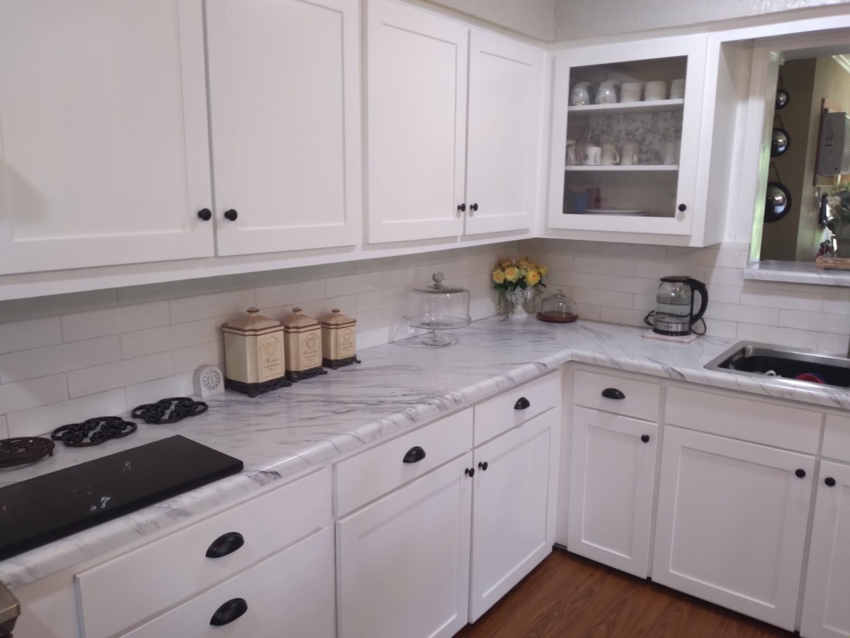 A clean and organized kitchen with white cabinets and a marble countertop.